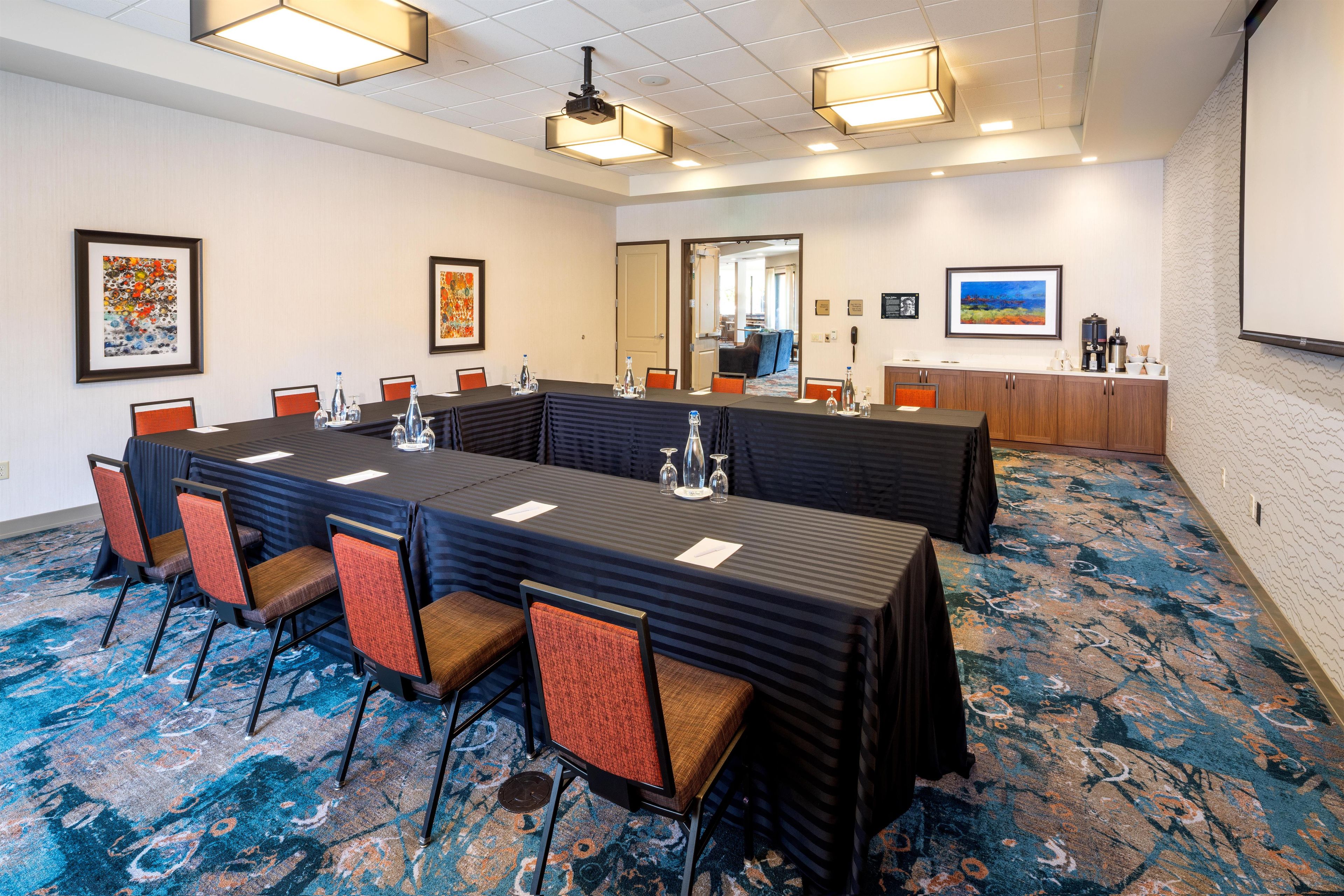 Une salle de conférence avec une longue table, des chaises et un sol recouvert de moquette.