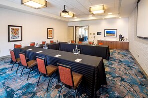 Un salón de conferencias con una mesa larga, sillas y piso alfombrado.
