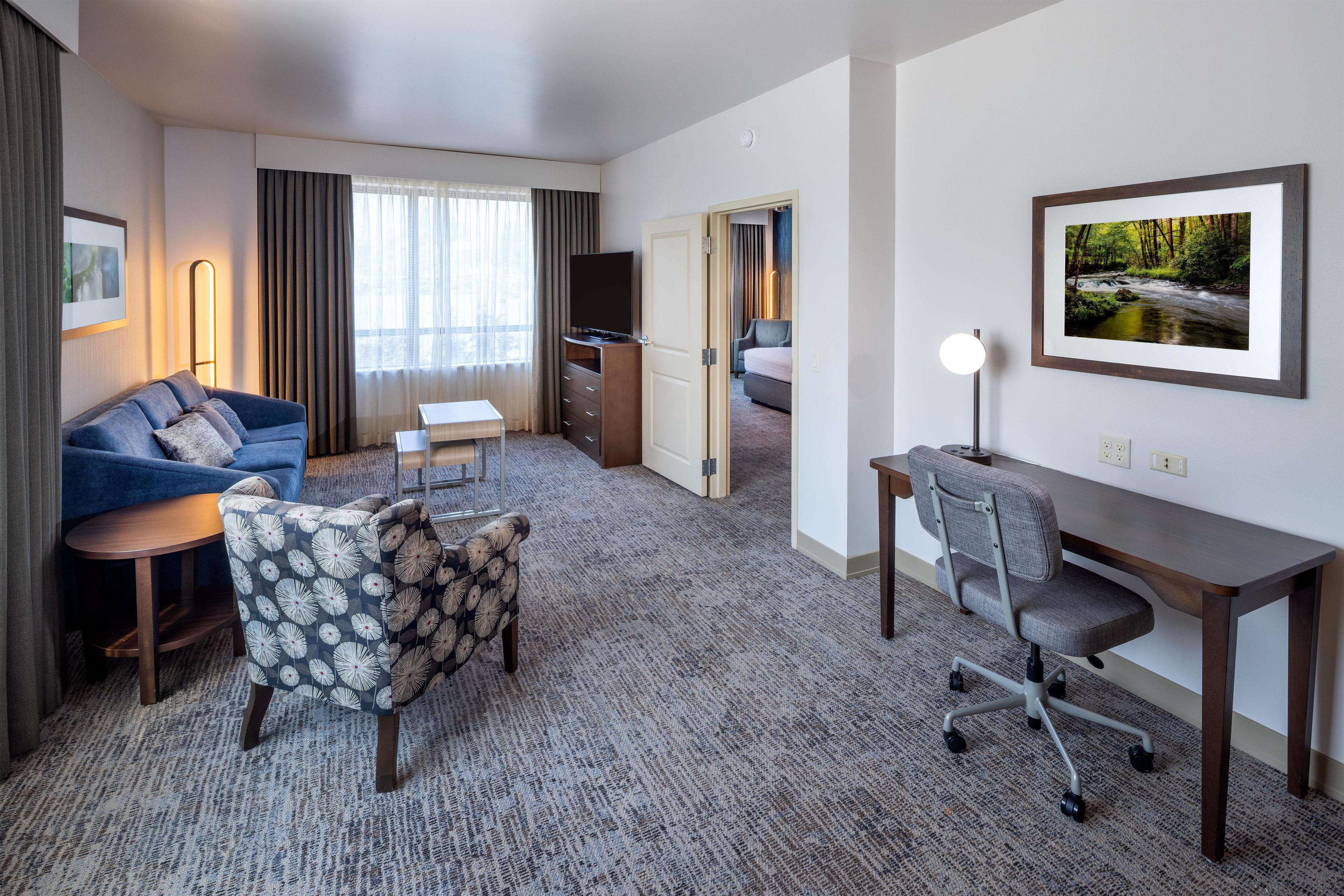 Ein Hotelzimmer mit einer Couch, einem Sessel, einem Schreibtisch und einem Bett.