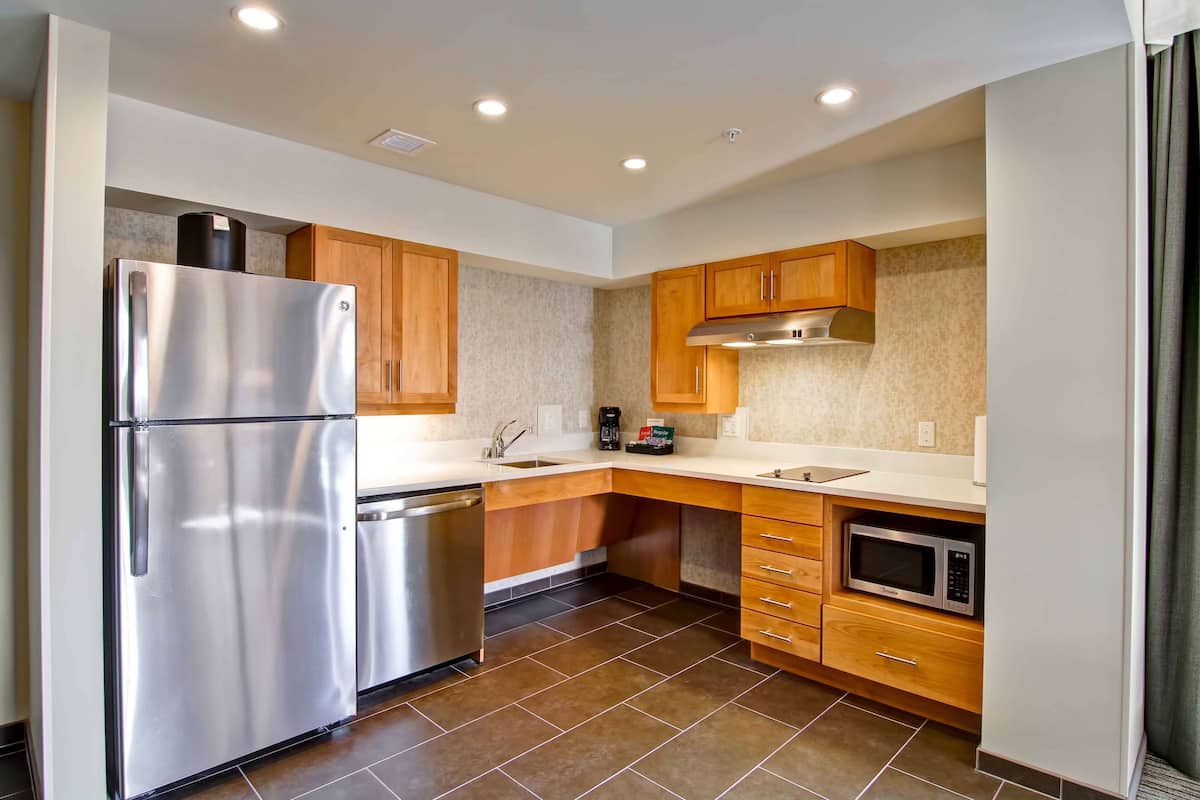 A modern kitchen with stainless steel appliances, wooden cabinets, and a tiled backsplash.