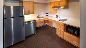 A modern kitchen with stainless steel appliances, wooden cabinets, and a black microwave.