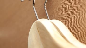 A wooden spoon hanging on a metal hook attached to a textured wall.