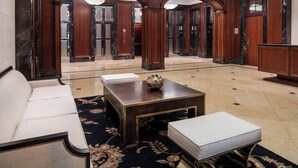 A lobby with a sofa, a coffee table, and an ottoman. There are wooden columns and a chandelier. - Residence Inn Chicago Downtown/Loop (Chicago)
