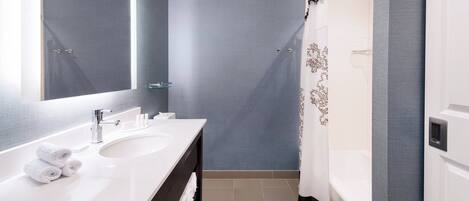 Un baño moderno con un espejo grande, dos lavamanos, una bañera y una cortina de ducha.