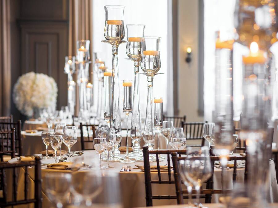 A long dining table set with multiple wine glasses and candles, surrounded by chairs.