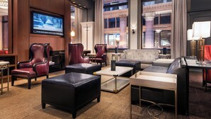 A hotel lobby with leather seating, a flat-screen TV, and large windows with a view of the cityscape. - Residence Inn Chicago Downtown/Loop (Chicago)