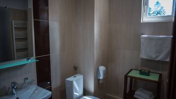 A bathroom with a toilet, sink, and a window.