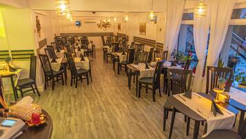 A restaurant with multiple tables and chairs, a sign indicating the exit, and a view of the outside through large windows.
