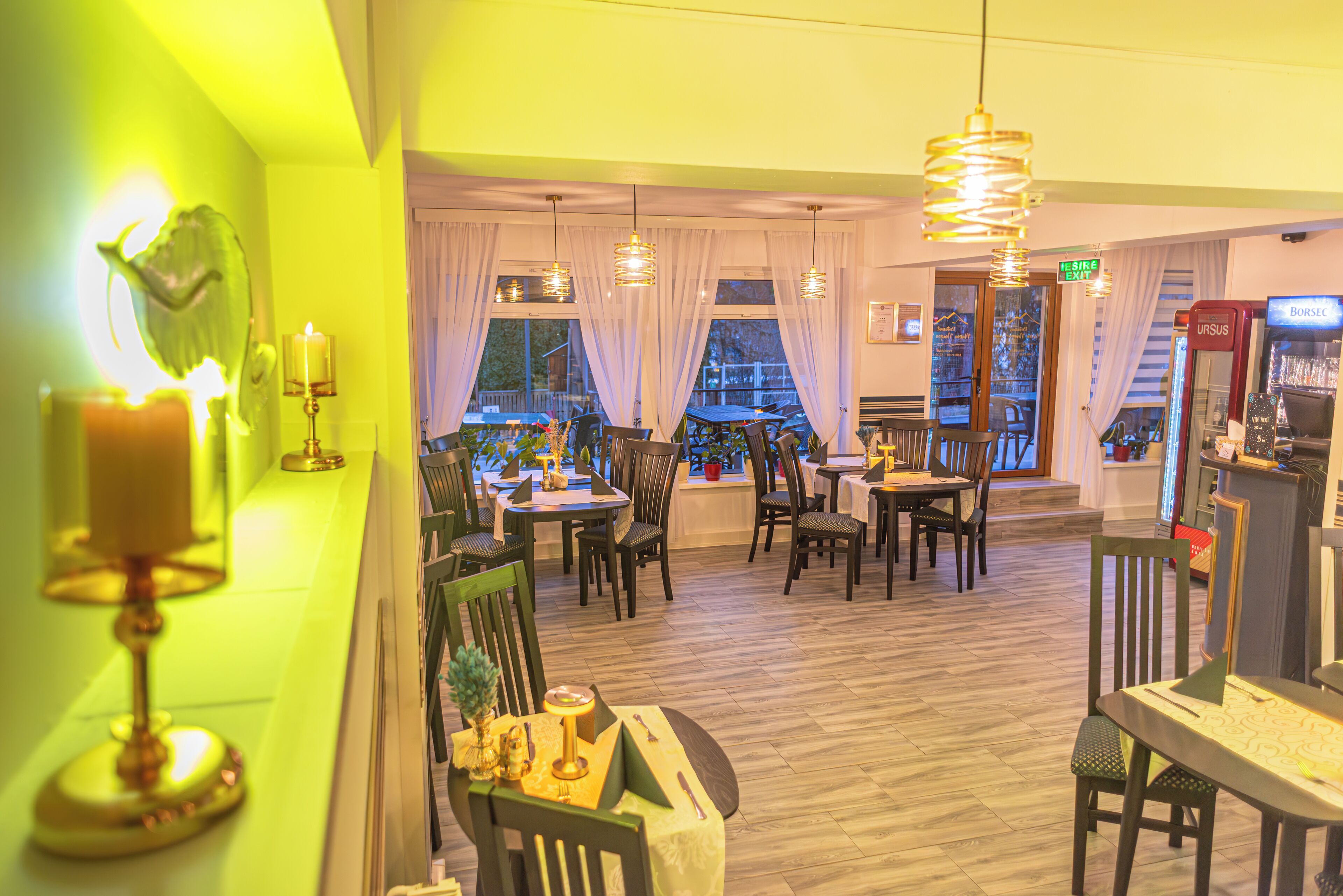 Een restaurant met houten vloeren, tafels, stoelen en hangende吊灯.