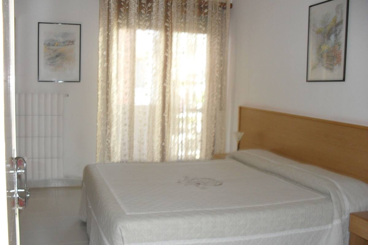 A bedroom with a bed, a radiator, and two framed pictures on the wall.