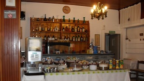 A bar area with shelves of liquor bottles, a cash register, and a table set for dining. - Hotel Ristorante Al Caminetto (Aosta)