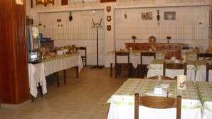 A dining area with multiple tables and chairs, a buffet counter, and a chandelier. - Hotel Ristorante Al Caminetto (Aosta)
