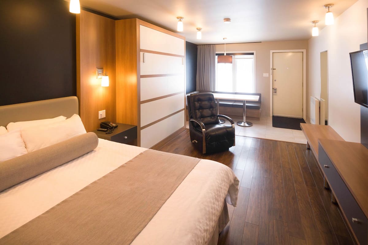 A hotel room with a large bed, a desk, a chair, a television, and a window with curtains.
