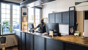 A reception desk with a computer, a phone, and a menu board in a modern hotel lobby.