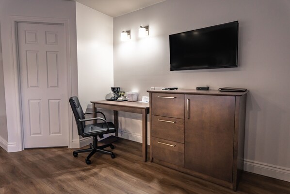 A room with a desk, chair, and a TV mounted on the wall. - Hotel Marineau La Tuque (La Tuque)