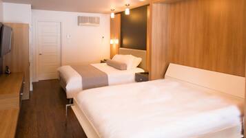 A hotel room with two beds, a wooden wardrobe, a flat-screen TV, and a wall-mounted air conditioner.