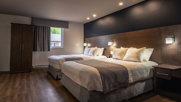 A modern bedroom with two beds, a wardrobe, and a nightstand.