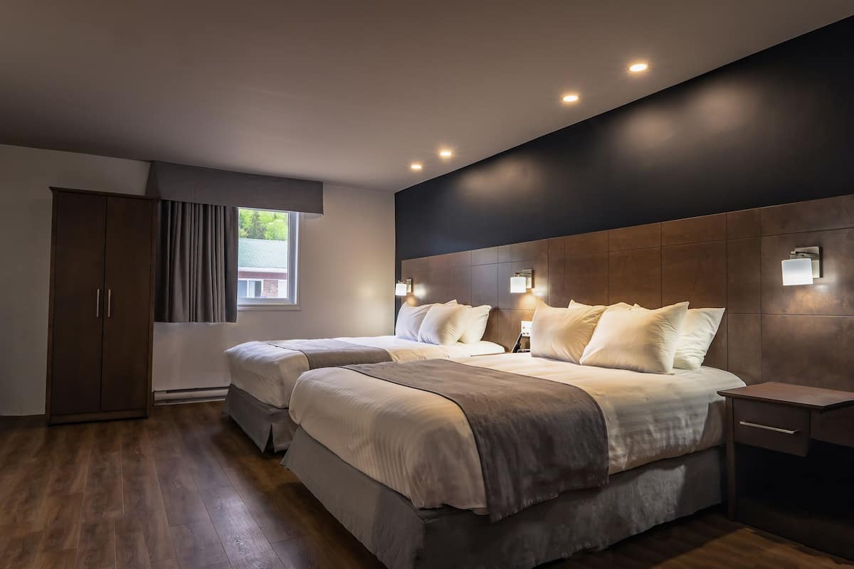 A modern bedroom with two beds, a wardrobe, and a nightstand.