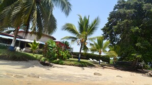 Une plage bordée de palmiers et un bâtiment surmonté d’un toit rouge.