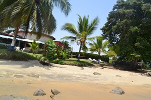 Una playa con palmeras y un edificio de techo rojo.
