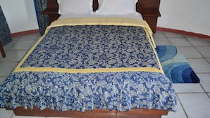 Un lit avec une couvre-lit bleue et jaune, une tête de lit en bois et des oreillers blancs.