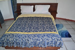 Una cama con una colcha azul y amarilla, un cabecero de madera y almohadas blancas.