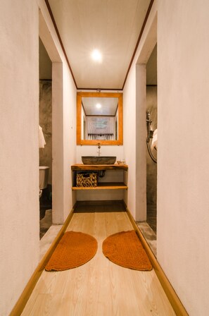 A narrow hallway with a wooden floor, a central sink with a wooden countertop, and a mirror above it. - Tan Thanh Garden Homestay (Da Nang)