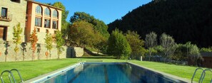 Piscina com um edifício de pedra e árvores ao fundo.