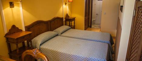 Une chambre d’hôtel avec deux lits, une tête de lit en bois, une table de chevet, une lampe et un miroir.