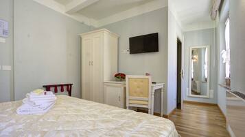 Une chambre d’hôtel comprenant un lit, une armoire, un bureau avec une chaise, un téléviseur à écran plat et un miroir.