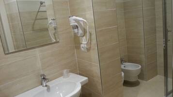 A bathroom with a sink, a mirror, a handheld showerhead, and a toilet.