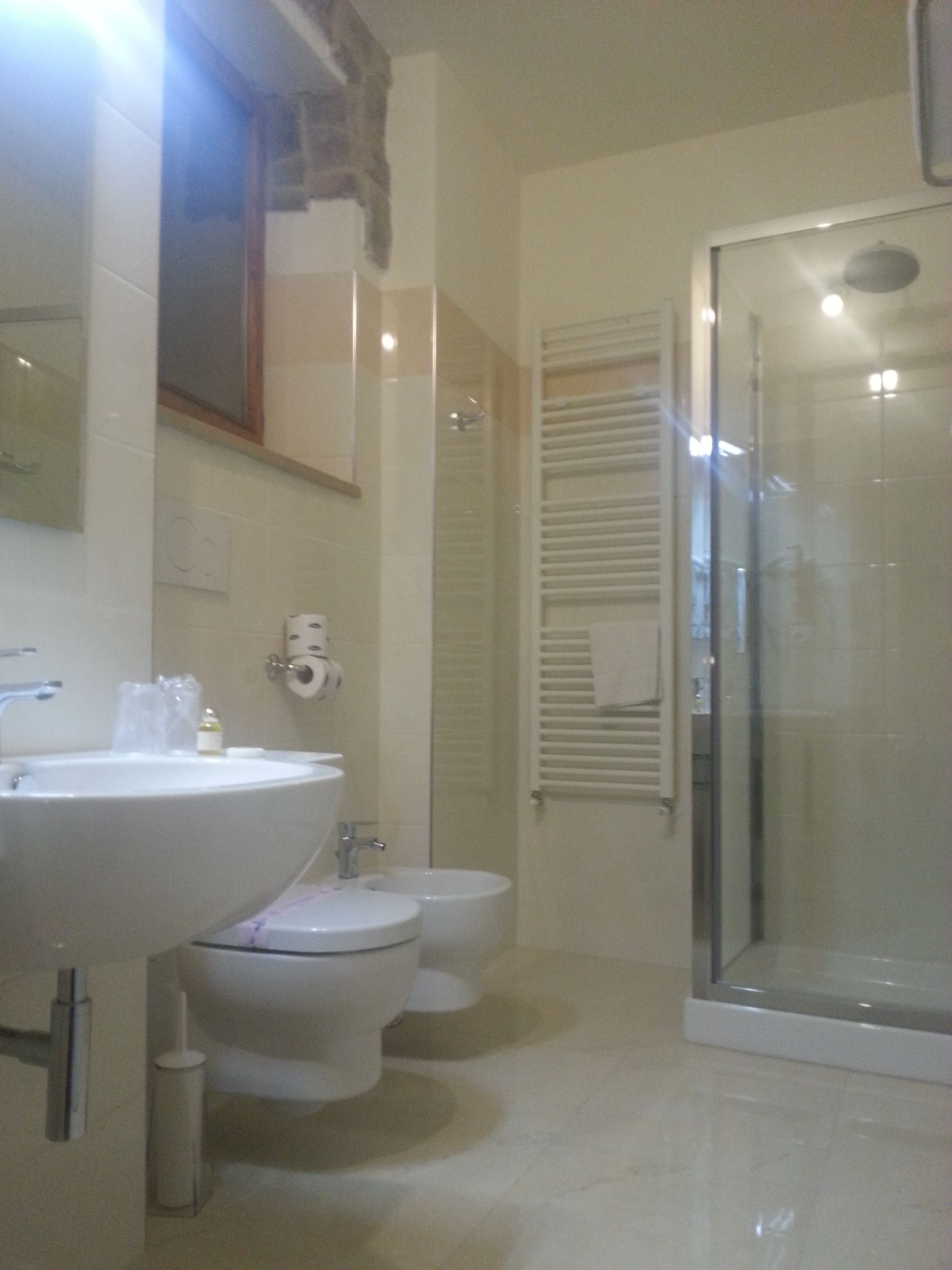 Une salle de bain équipée d’un lavabo, de toilettes, d’un bidet et d’une douche à parois en verre.