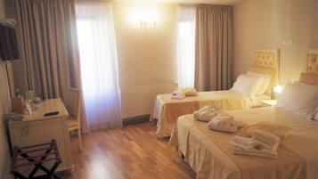 A hotel room with two beds, a desk, a chair, and a TV.