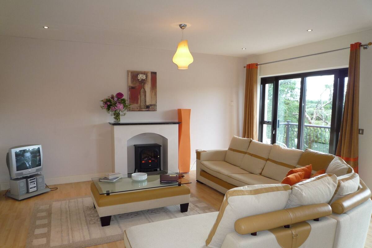 A living room with a sofa, a fireplace, a television, and a large window.