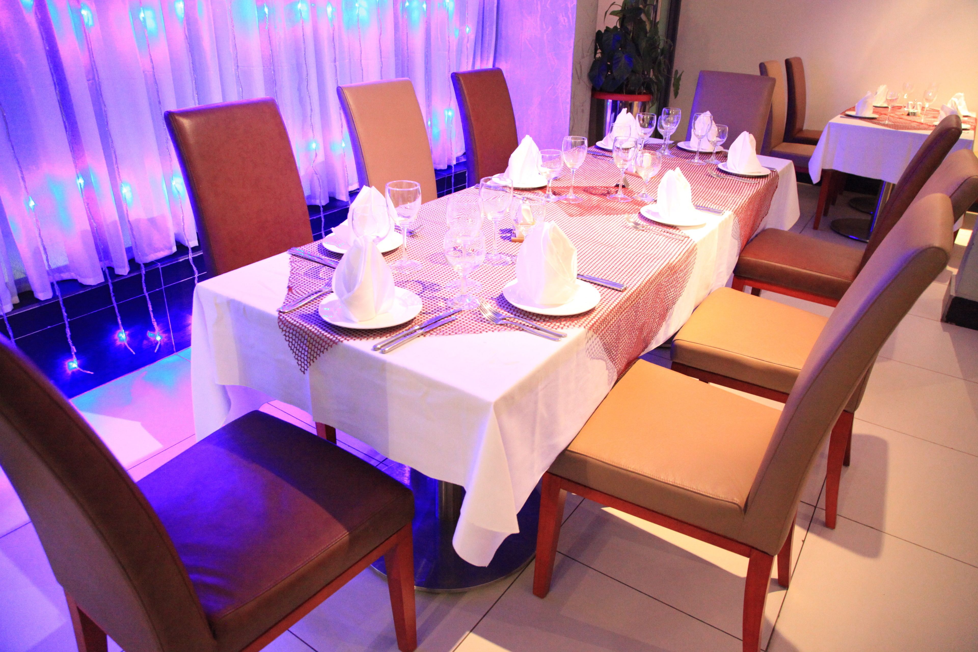 A dining area with a long table set for a meal, surrounded by chairs.