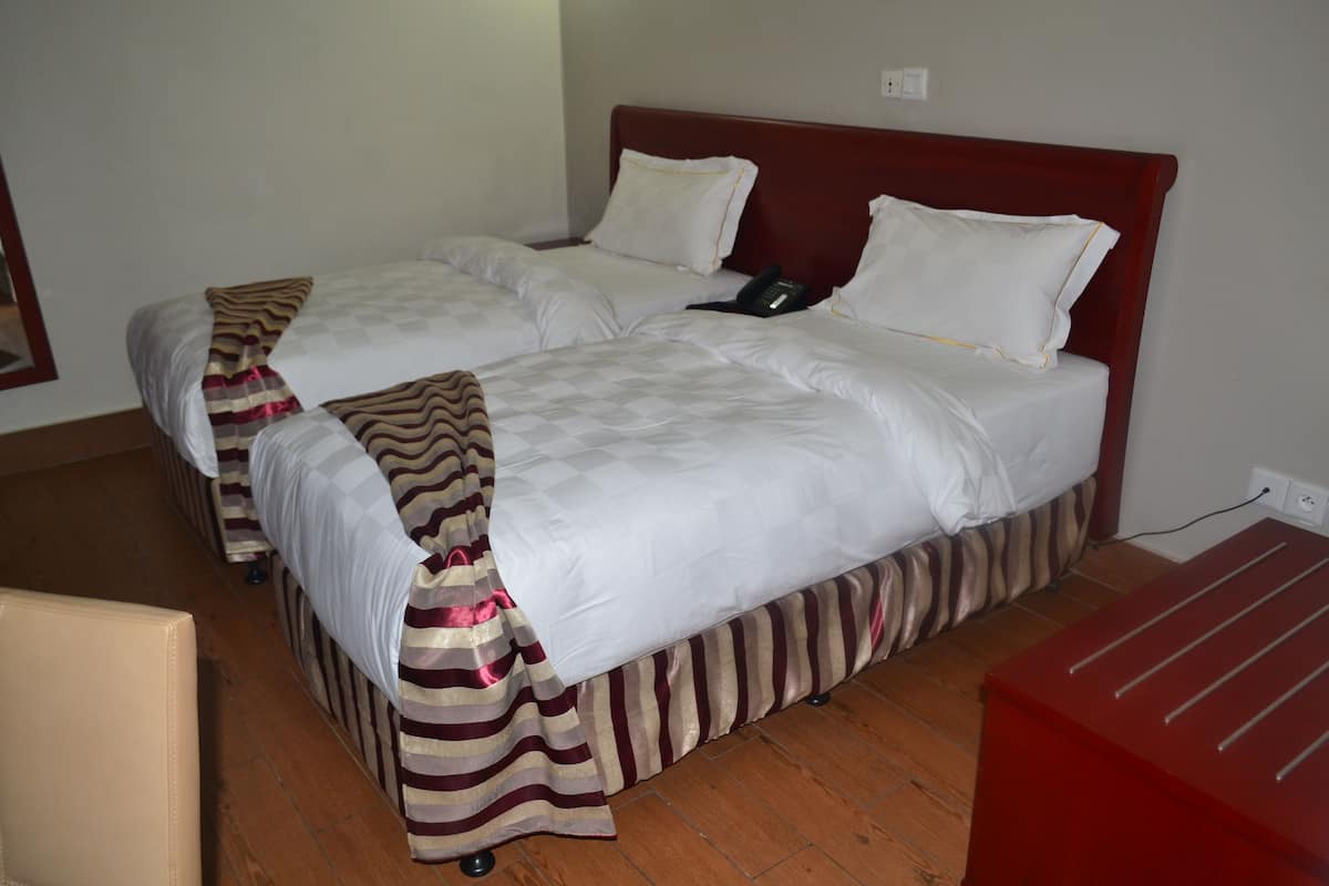 A hotel room with two beds, each with white bedding and striped curtains.