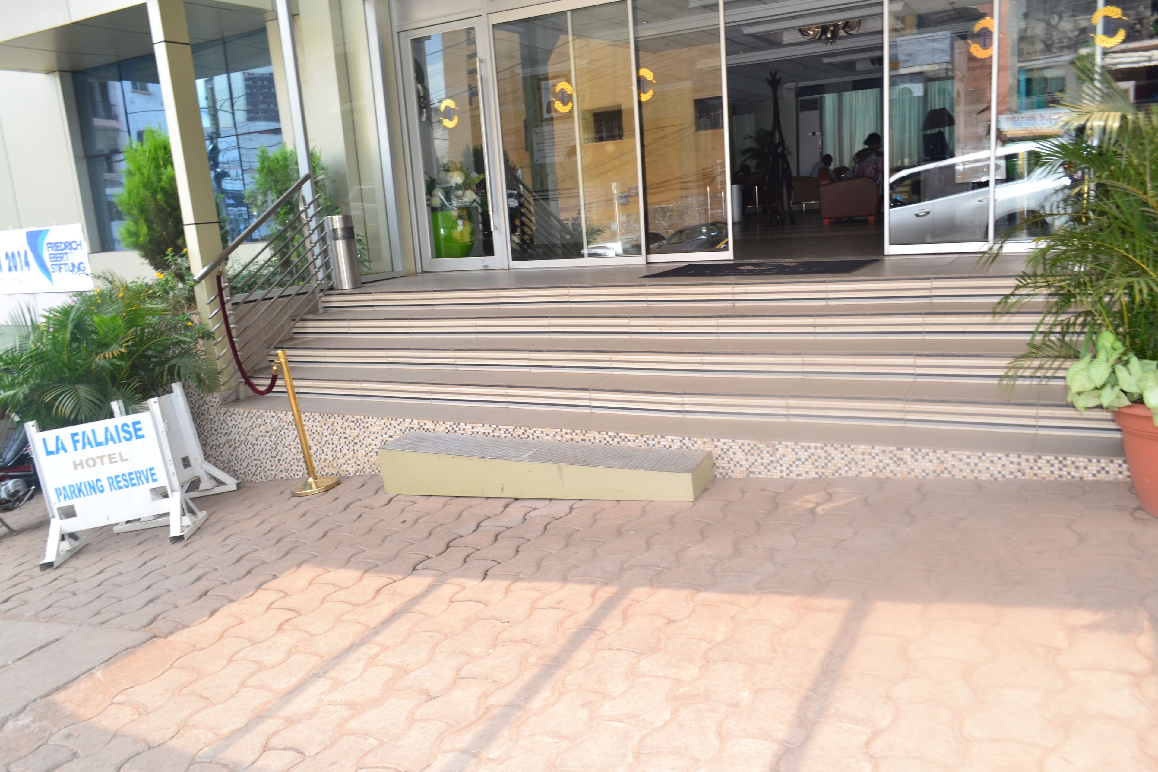 Ein Hotel Eingang mit Glastür, einer nach oben führenden Treppe und einem Schild, das reservierte Parkplätze kennzeichnet.