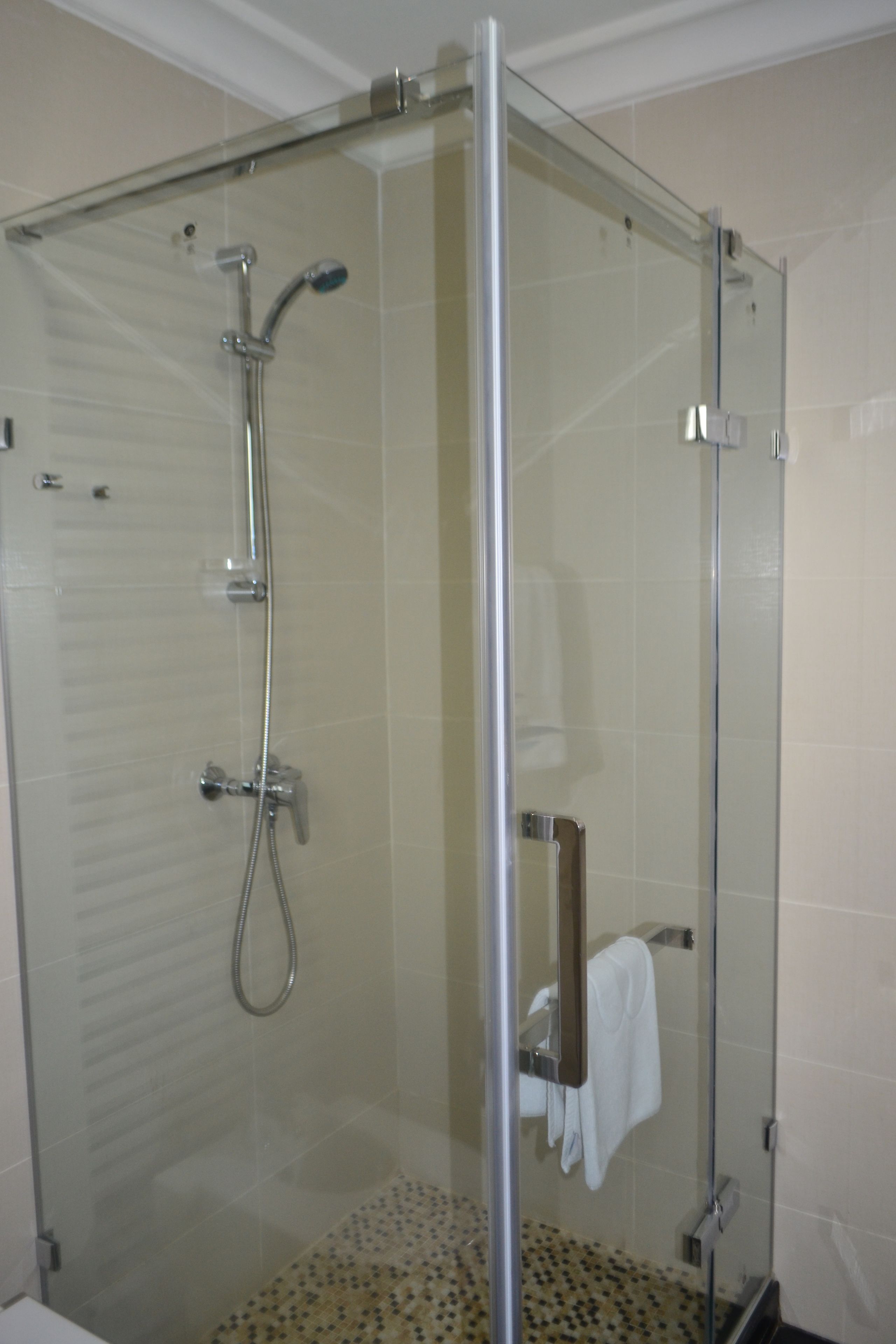 Eine Duschkabine mit Handbrause und am Wand montiertem Wasserhahn.