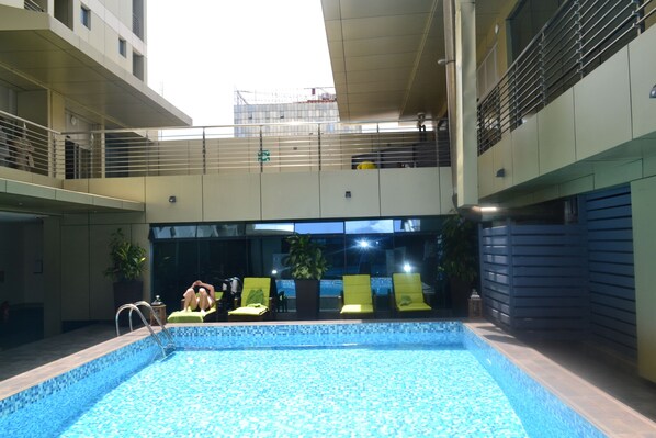 Una piscina al aire libre, sillones reclinables de piscina