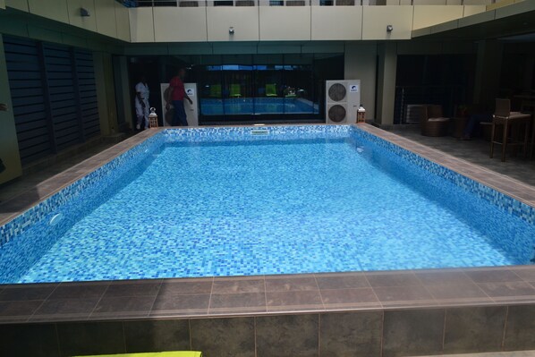 Una piscina interior con borde de azulejos, rodeada de suelo y paredes revestidas de azulejos.