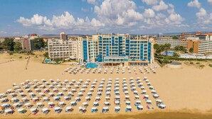 Un hôtel à étages, doté d’une piscine et d’une vaste plage avec de nombreux transats.