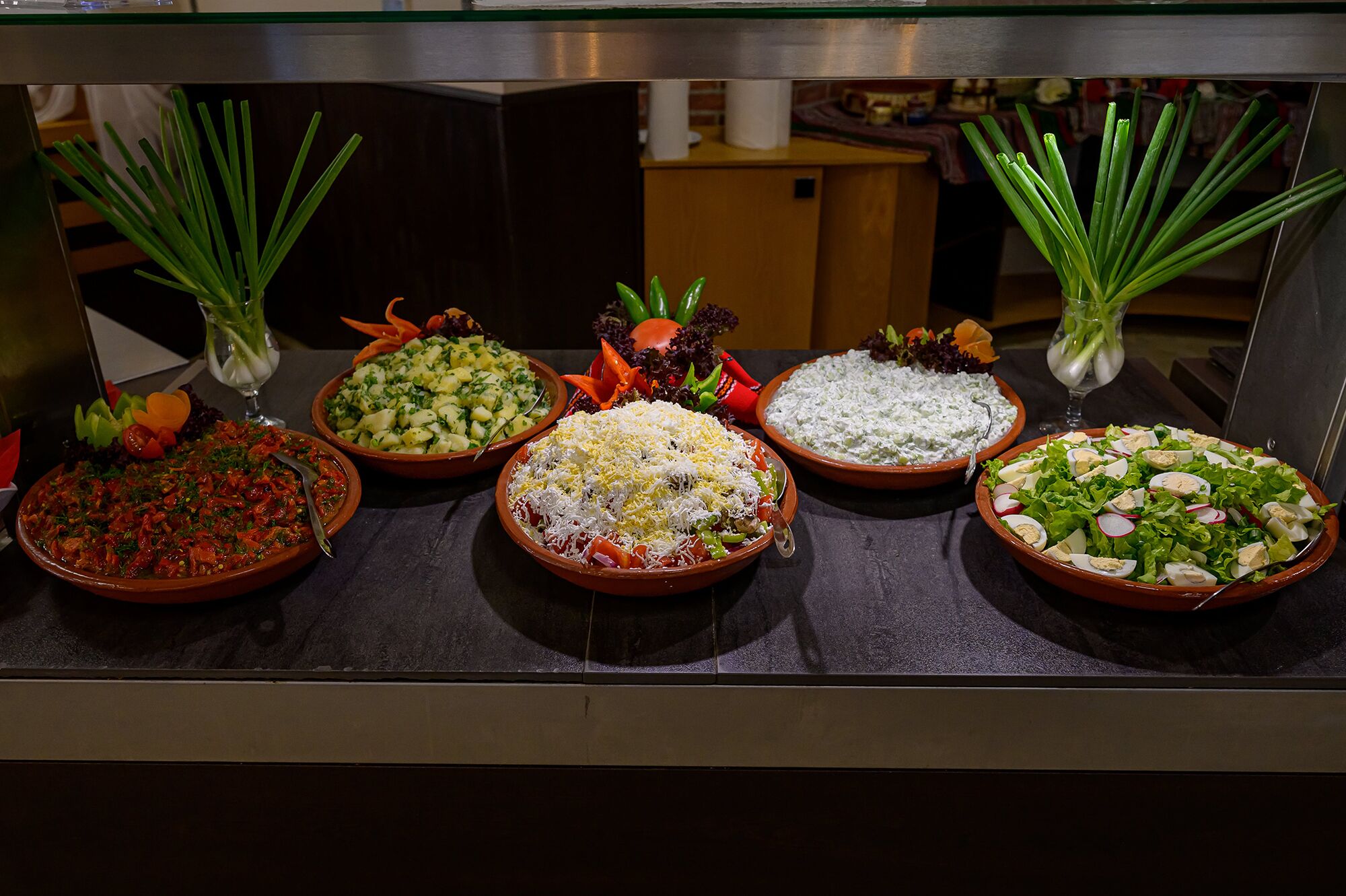 A buffet with various dishes including salads, pasta, and a meat dish.