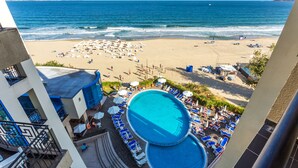 Un complexe hôtelier en bord de mer doté d’une piscine, de chaises longues et offrant une vue sur l’océan.
