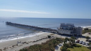 Un muelle que se adentra en el océano, con un edificio cerca de la playa.