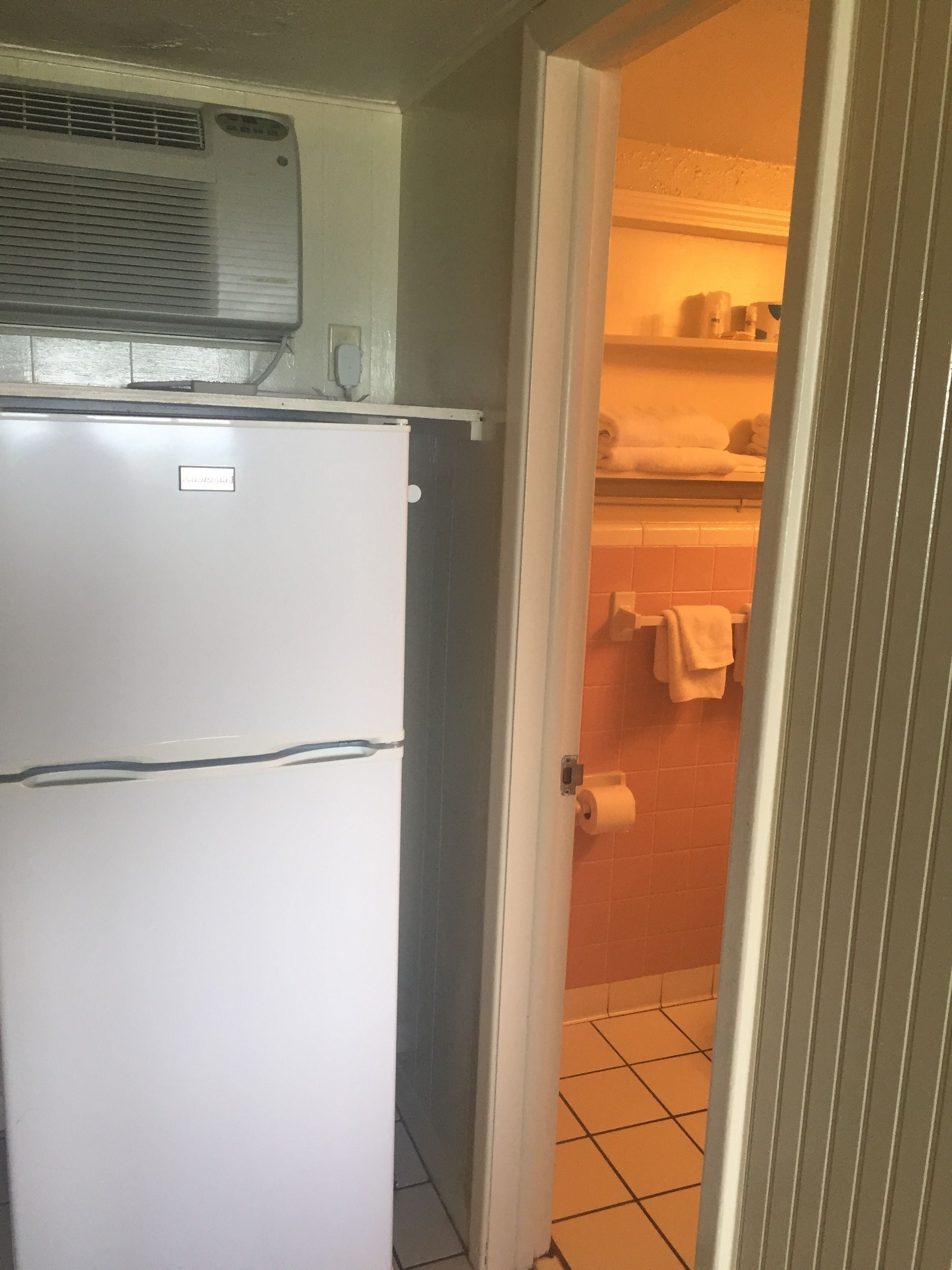 Eine kleine Küche mit einem weißen Kühlschrank, einer Arbeitsplatte und einer gefliesten Spritzschutzwand.