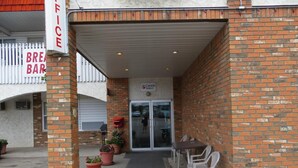 A brick building with a covered entrance, a sign for a Canada Select store, and outdoor seating with potted plants.
