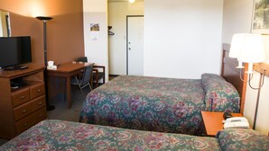 A hotel room with two beds, a desk with a chair, a television, and a lamp.
