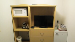 A kitchenette with a microwave, coffee maker, and a flat-screen TV.