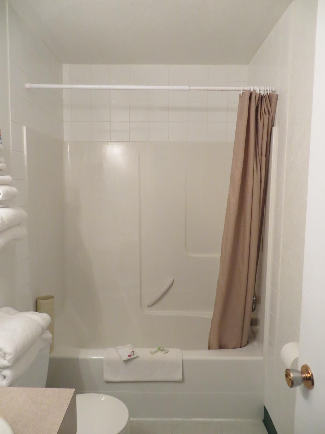 A bathroom with a bathtub, toilet, and a towel rack with folded towels.