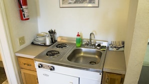 A compact kitchen with a stove, sink, and dishwasher.